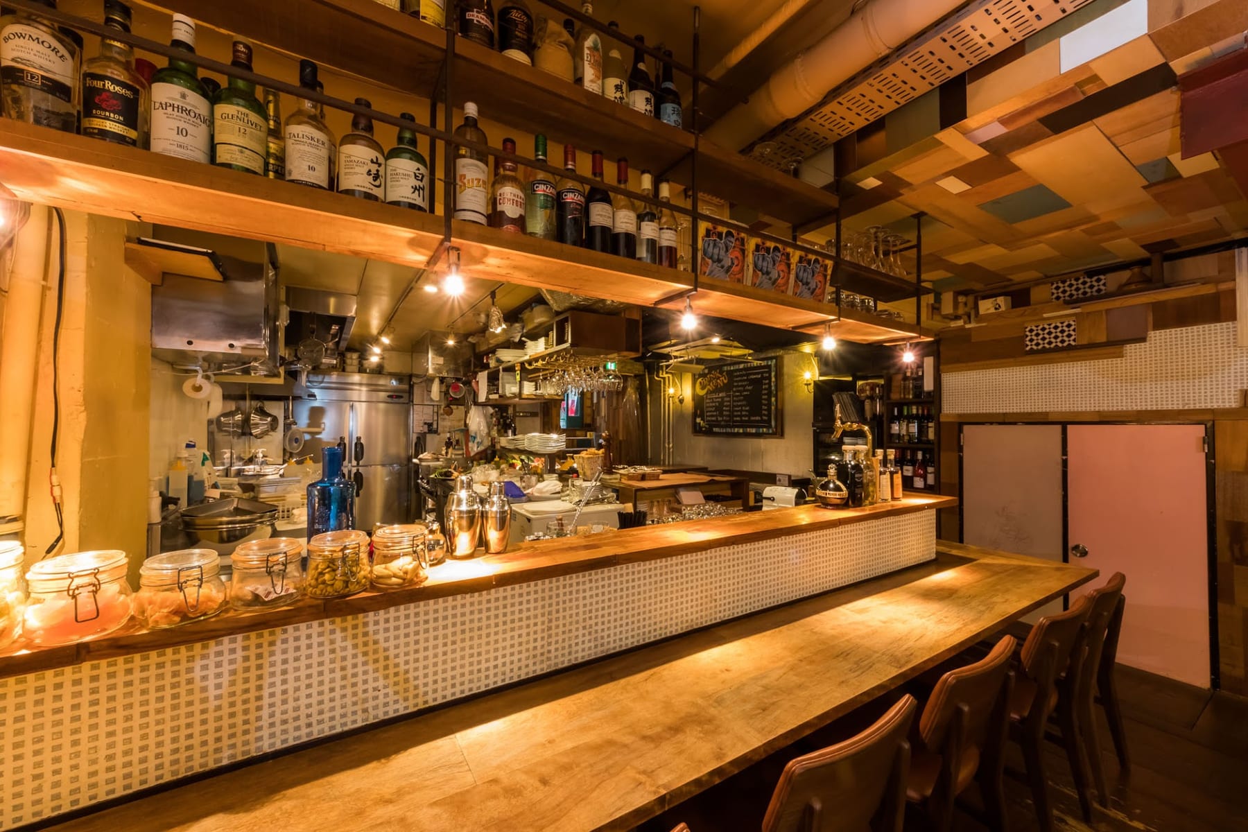 木のカウンターと上段に並ぶ酒瓶、暖かな照明がともる店内